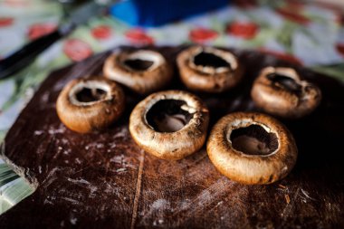 Ahşap bir tabakta pişmeye hazır kahverengi mantarlı (Agaricus bisporus) sığ alan derinliği (seçici odak) ayrıntıları.