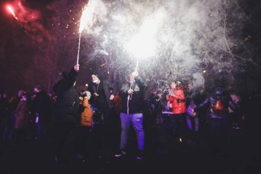 Bükreş, Romanya - 1 Ocak 2022: Bükreş 'teki bir parkta düzenlenen yeni yıl kutlamaları sırasında insanlar havai fişek atarken, sığ alan derinliği (seçici odak) duman ve pırıltılarla ilgili ayrıntılar.