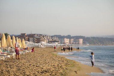 Obzor, Bulgaristan - 18 Ağustos 2021: Bulgaristan 'ın Obzor tatil beldesindeki Karadeniz' de sakin ve sıcak bir yaz sabahında sahil, kum ve oteller.