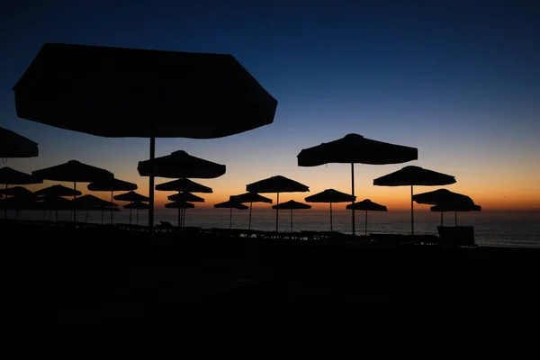 Σιλουέτες Ομπρέλες Ηλίου Στην Παραλία Λίγο Πριν Την Ανατολή Του — Φωτογραφία Αρχείου