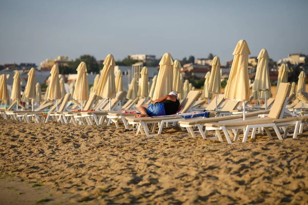 Man Sitting Lounge Chair Beach Calm Warm Summer Morning Black — Zdjęcie stockowe