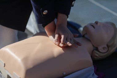 Eğitim amaçlı manken üzerinde kardiyopulmoner resüsitasyon (kalp masajı) yapmayı öğrenen bir kız öğrencinin elleriyle ilgili detaylar.