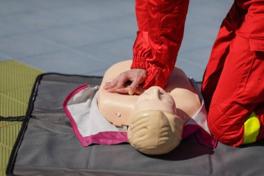 Eğitim amacıyla manken üzerinde kardiyopulmoner resüsitasyon (CPR) uygulayan bir acil tıp görevlisinin elleriyle ilgili detaylar.