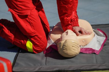 Eğitim amacıyla manken üzerinde kardiyopulmoner resüsitasyon (CPR) uygulayan bir acil tıp görevlisinin elleriyle ilgili detaylar.