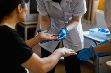Kadın bir sıhhiyecinin ve bir kadının dermatolojik sağlığını kontrol eden kadın asistanın ellerindeki detaylar..