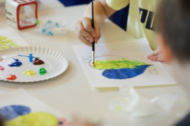 Bükreş, Romanya - 9 Mayıs 2022: Ukraynalı mülteci çocukların bayrakları çizdiği sığ alan derinliği (seçici odak) ayrıntıları.