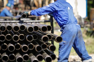 Petrol sondaj boruları arka planda petrol endüstrisi işçileriyle dolu. Petrol ve gaz endüstrisi. Petrol sahasında ham petrol pompası krikosu. Petrol ve gaz kuyularının kazılması.