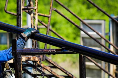 Oil and gas industry worker operates oil rig drill pipes on an oil well rig.