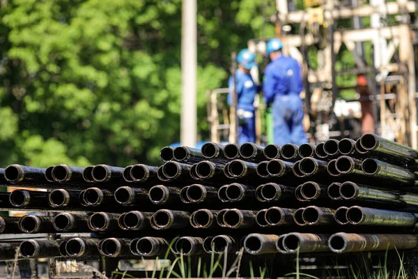 以石油工业工人为背景的石油钻机钻管堆积如山 石油和天然气工业 油田上的原油泵千斤顶 钻探石油和天然气井 — 图库照片
