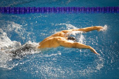 Olimpik yüzme havuzu kelebeği stilinde yüzen profesyonel bir erkek sporcunun detayları..