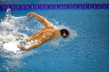Otopeni, Romania - 8 July 2022: Details with a professional Austrian male athlete swimming in an olympic swimming pool butterfly style.