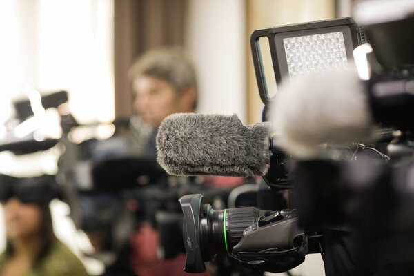 Shallow depth of field (selective focus) details with the microphones and lenses of news tv cameras during a press event