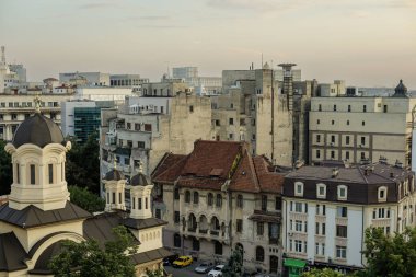 Bükreş, Romanya - 30 Temmuz 2022: Bükreş 'in eski kısmı, yaz günbatımında birlikte yeni ve eski binalar ve arka planda Parlamento Sarayı ile birlikte.