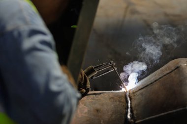 Bucharest, Romania - September 8, 2022: Shallow depth of field (selective focus) details with a professional welder welding an industrial metallic pipeline.