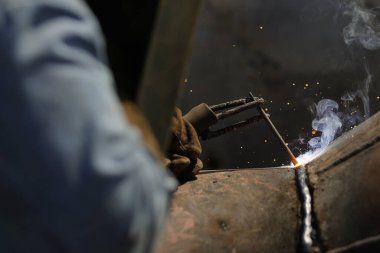 Bucharest, Romania - September 8, 2022: Shallow depth of field (selective focus) details with a professional welder welding an industrial metallic pipeline.