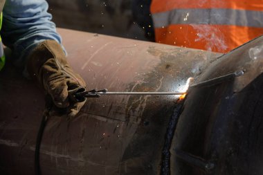 Bucharest, Romania - September 8, 2022: Shallow depth of field (selective focus) details with a professional welder welding an industrial metallic pipeline.