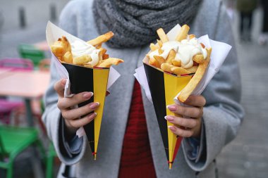 Belçika usulü patates kızartması ve Brüksel, Belçika 'da mayonez. Kadın turist sokakta iki porsiyon patates kızartması tutuyor..