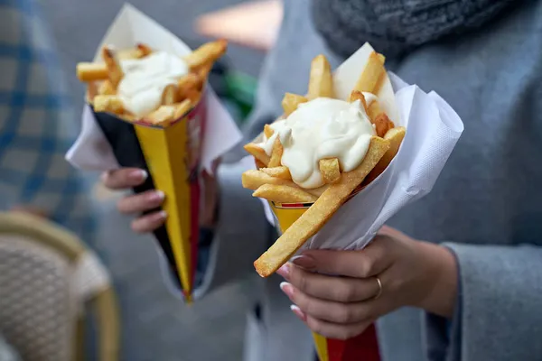 Papas fritas belgas o papas fritas con mayonesa en Bruselas, Bélgica. Turista femenina sostiene dos porciones de papas fritas en las manos en la calle. — Foto de Stock