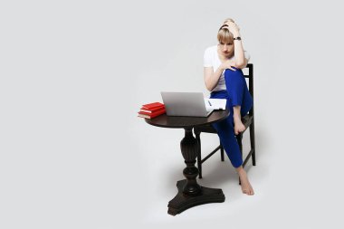 Masada oturan odaklanmış genç kız öğrenci bilgisayar ekranına bakarken online olarak çalışıyor ya da çalışıyor. Uzaktan öğrenme ya da evden uzak çalışma. Beyaz arkaplanda izole.