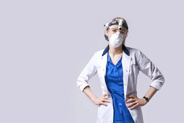 Fiducioso medico ENT che indossa lanterna frontale del faro chirurgico, maschera protettiva e occhiali. Ritratto di otorinolaringoiatra o di chirurgo testa e collo su sfondo grigio chiaro. — Foto Stock