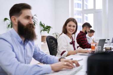 Modern bilişim ofisinde çalışan insanlar. Bir grup genç programcı ve yazılım geliştirici bilgisayar üzerinde çalışan masalarda oturuyorlar. Ekip iş başında.
