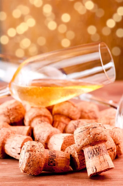 A glass of Champagne over corks with lights background — Stock Photo, Image