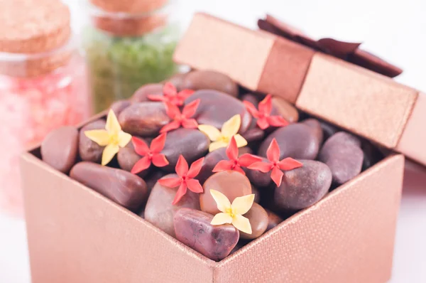 Pedras zen vermelhas em uma caixa de presente de bronze com flores vermelhas e amarelas — Fotografia de Stock