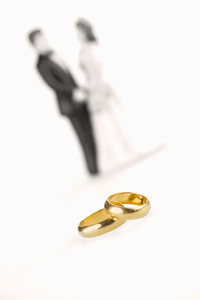 Pure gold wedding rings and porcelain bride and groom background — Stock Photo, Image