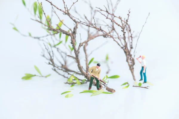 Miniature workmen cutting trees together — Stock Photo, Image