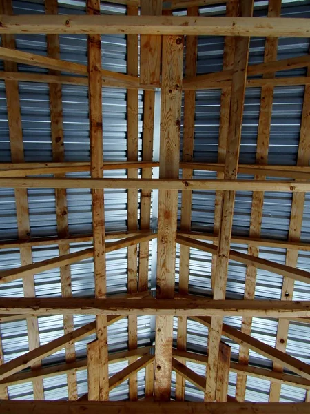 Corrugated steel and wooden beams roof for storage or open-air pavilion.