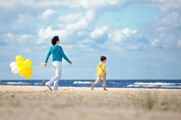 Mamma och Lille son med ballonger på stranden — Stockfoto