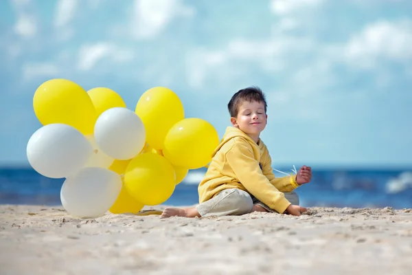 Milý chlapeček s balónky na pláži — Stock fotografie