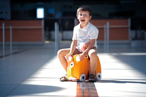 Cute little boy with orange suitcase at airport — Stock Photo, Image