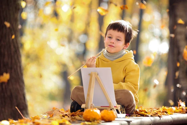 Cute little boy painting in golden autumn park — Stock Photo, Image
