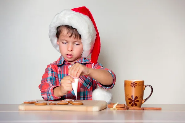 Симпатичный маленький мальчик украшает пряничное печенье — стоковое фото
