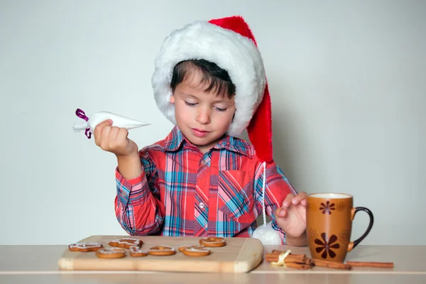 Cute little boy decorating the gingerbread cookies — Stockfoto