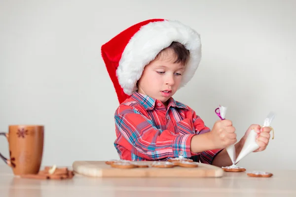 Netter kleiner Junge dekoriert die Lebkuchen — Stockfoto