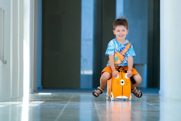 Cute happy boy with a suitcase at airport — Stock Photo, Image