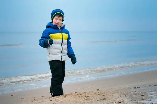 Milý chlapeček hraje na zimní beach — Stock fotografie