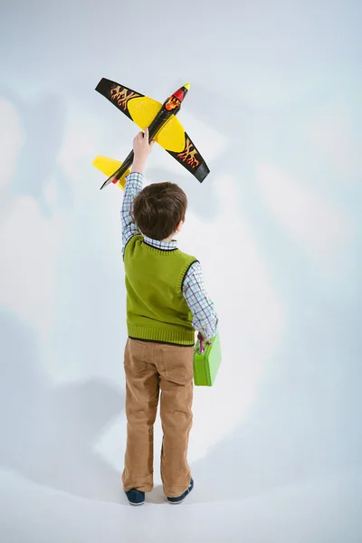 Menino segurando um modelo de avião e bolsa — Fotografia de Stock