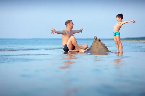 Молодой отец и его сын веселятся на пляже — стоковое фото