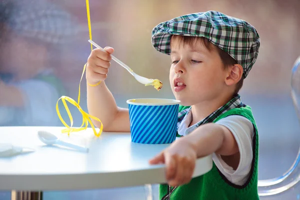 Bonito menino comendo sorvete no café interior — Fotografia de Stock