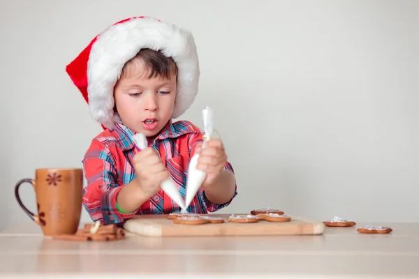 Cute little boy decorating the gingerbread cookies — ストック写真