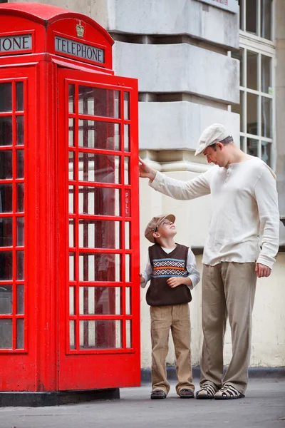 Отец и сын на улице возле красной телефонной будки — стоковое фото