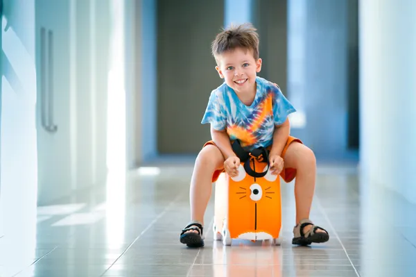 Bonito menino feliz com uma mala no aeroporto — Fotografia de Stock