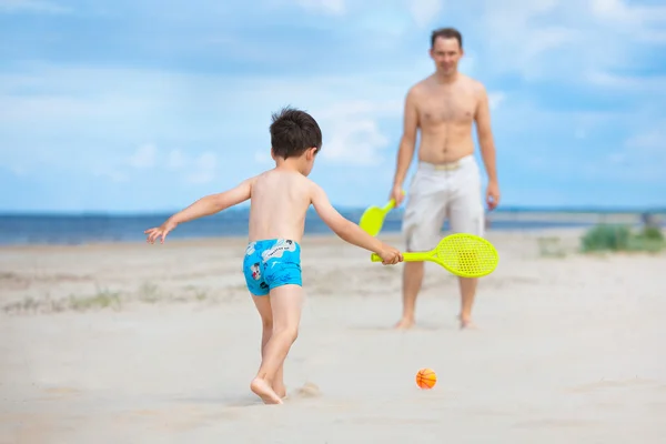 Отец и сын играют в теннис на пляже — стоковое фото