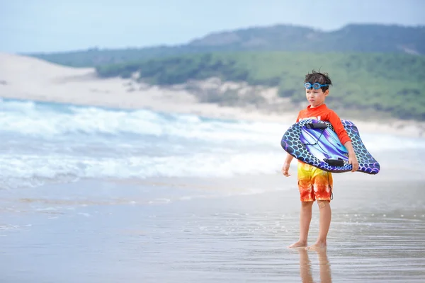 Six years old boy with surf board on exotic beach — Stock Photo, Image