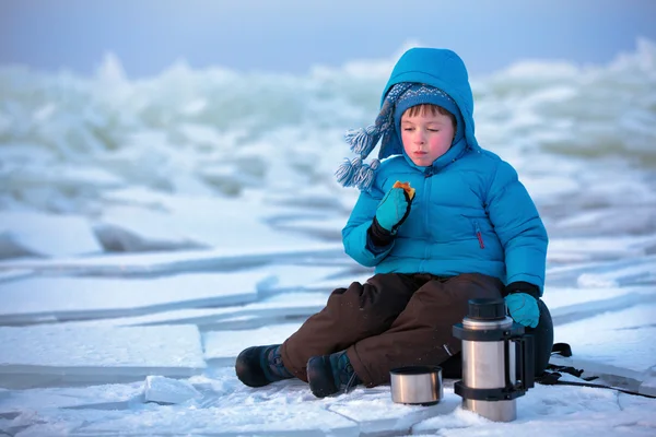 Χαριτωμένο μικρό αγόρι που έχοντας ένα πικ-νικ στην παραλία του χειμώνα — Φωτογραφία Αρχείου