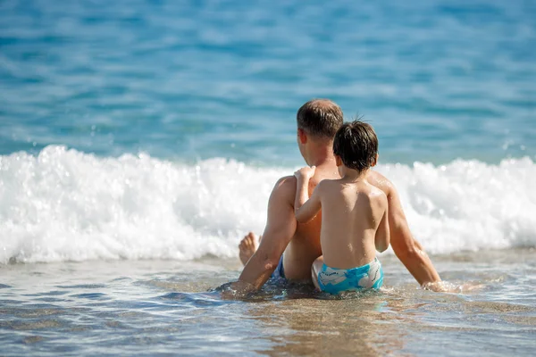 Pai e filho relaxando nas ondas do oceano — Fotografia de Stock