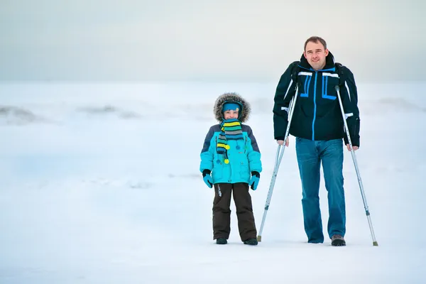 Man med kryckor och hans son promenader utomhus — Stockfoto